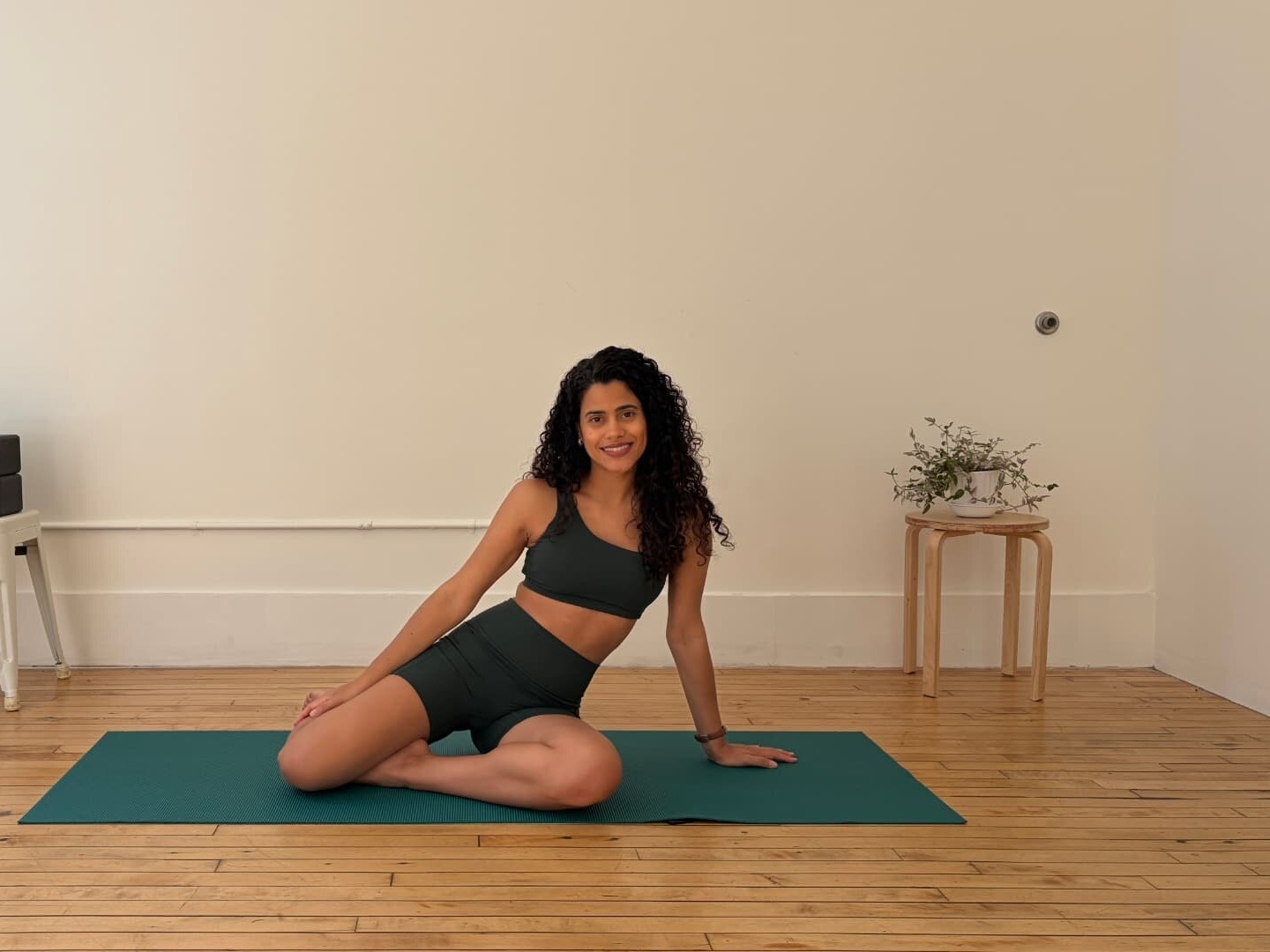 A woman seated on a mat in a bright studio after a mobility practice